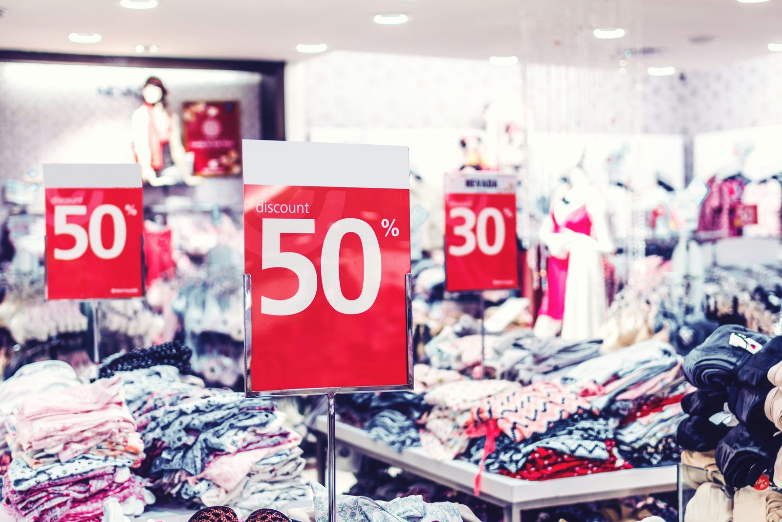 Interno di negozio con cartelli di sconto su scaffali di abbigliamento